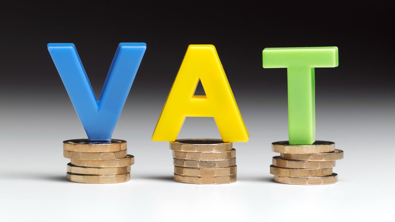 Letters spelling VAT balancing on pound coins