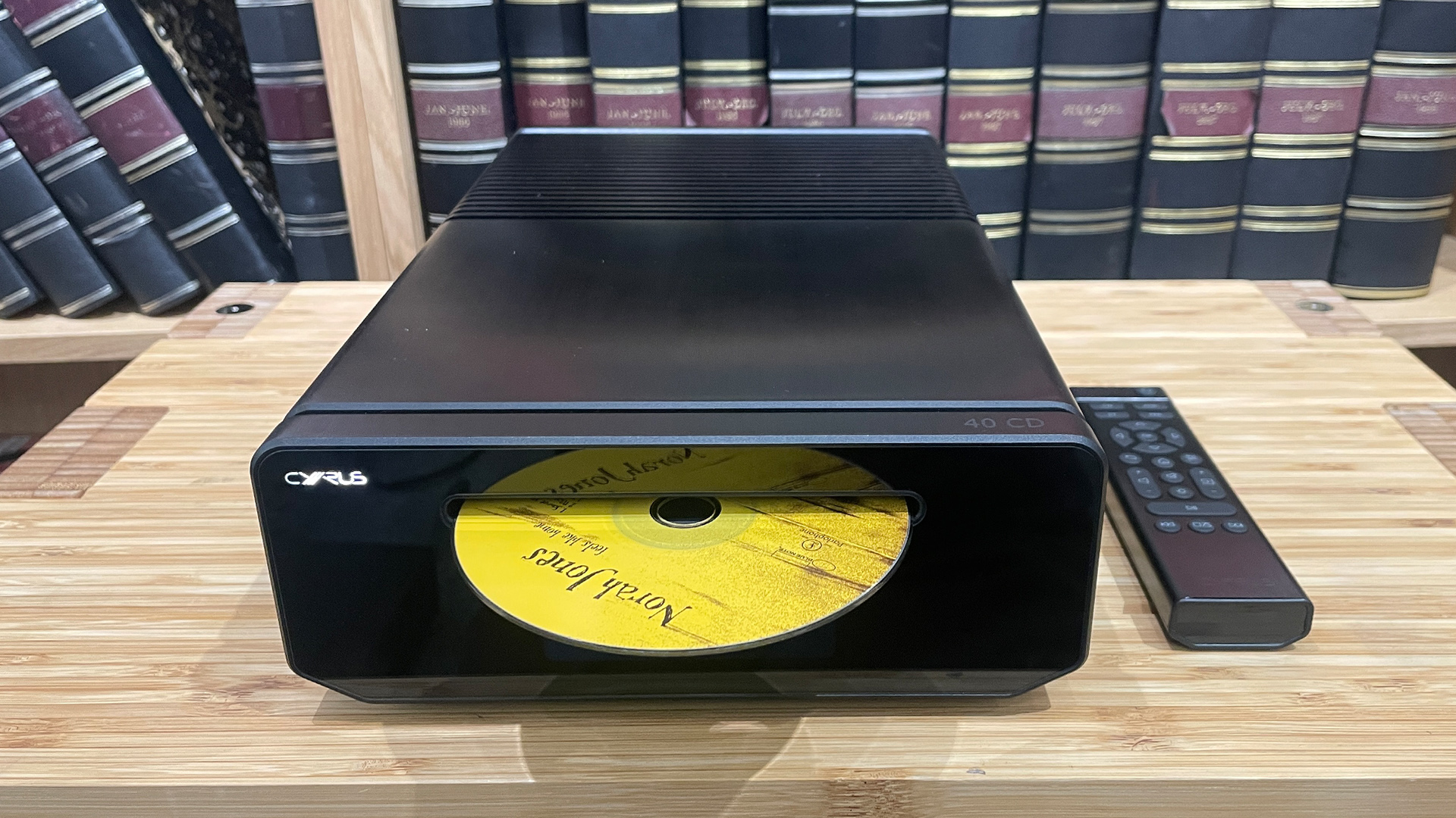 Cyrus 40 CD CD player on wooden hi-fi rack in front of book case, Norah Jones CD is half in player