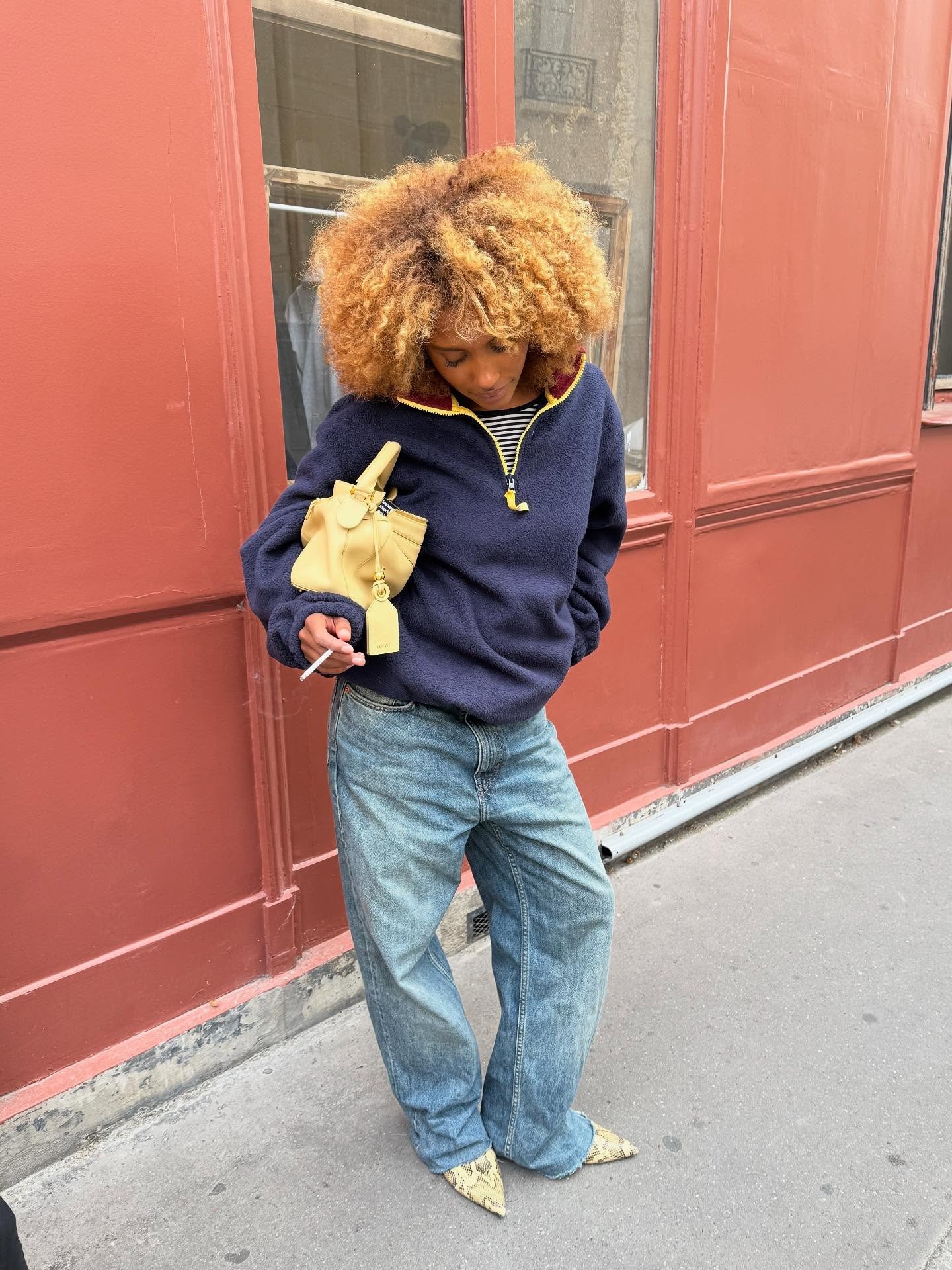 A woman wearing a stylish outfit in Paris, with a curly, layered hairstyle