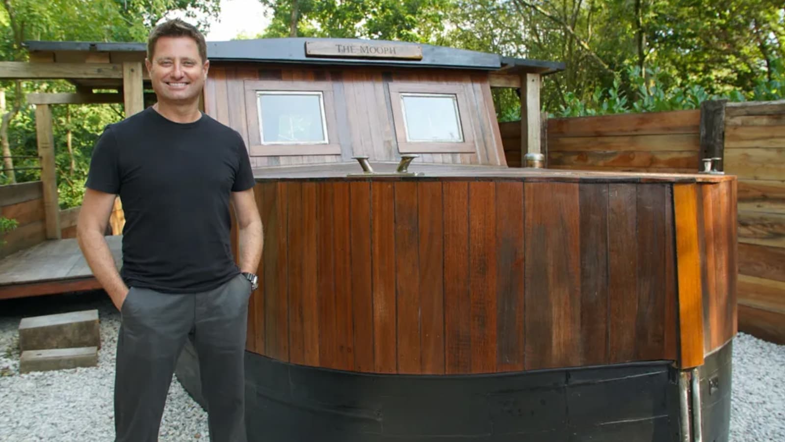 George Clarke standing on a boat converted into a house