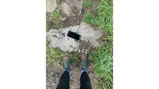 A smartphone lying at a hikers feet on the trail