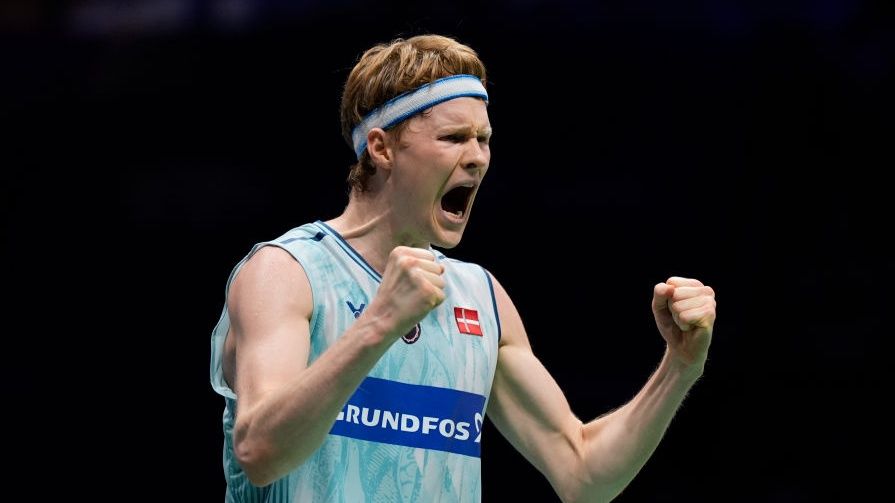 Badminton player Anders Antonsen of Denmark, wearing light blue sweatband and vest, clenches his fists in victory ahead of his appearance at the BWF World Tour Badminton Finals 2024