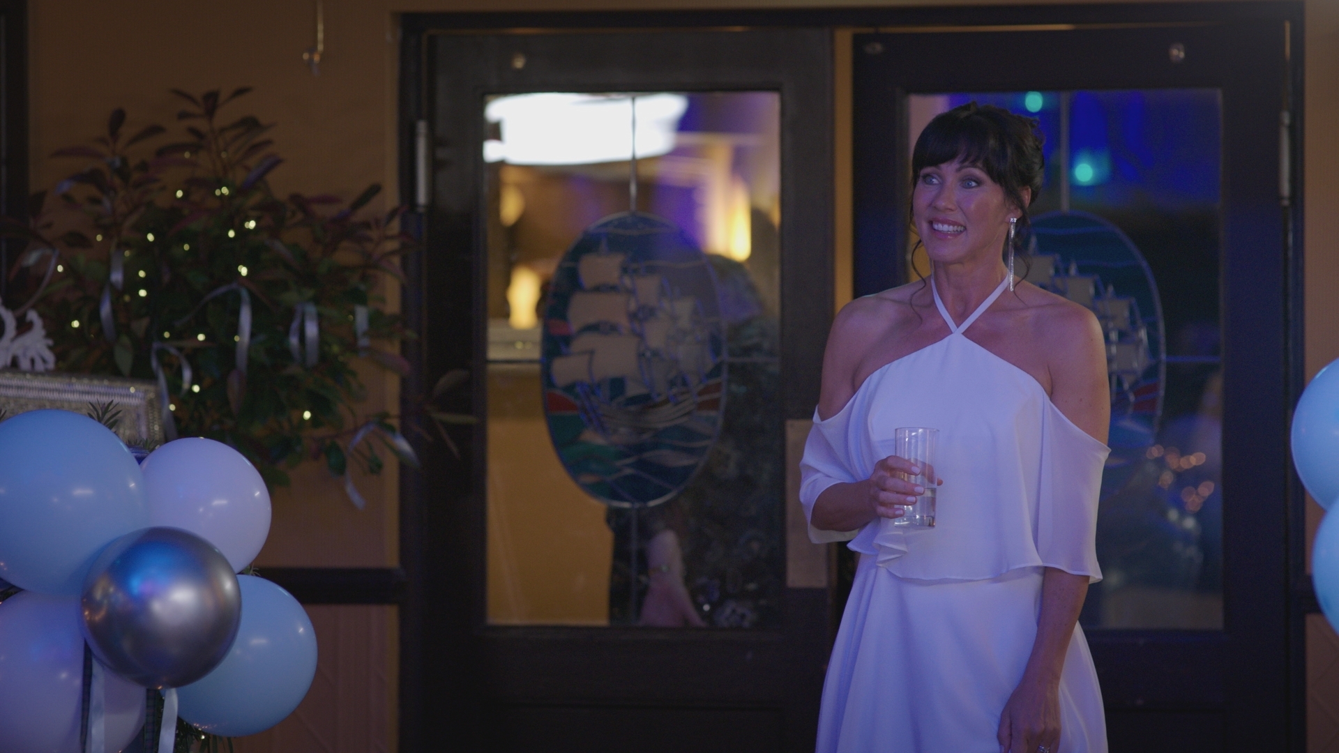 Stevie Nash is nowhere to be seen as Faith smiles nervously in a halter neck wedding gown, holding a drink at her wedding reception.
