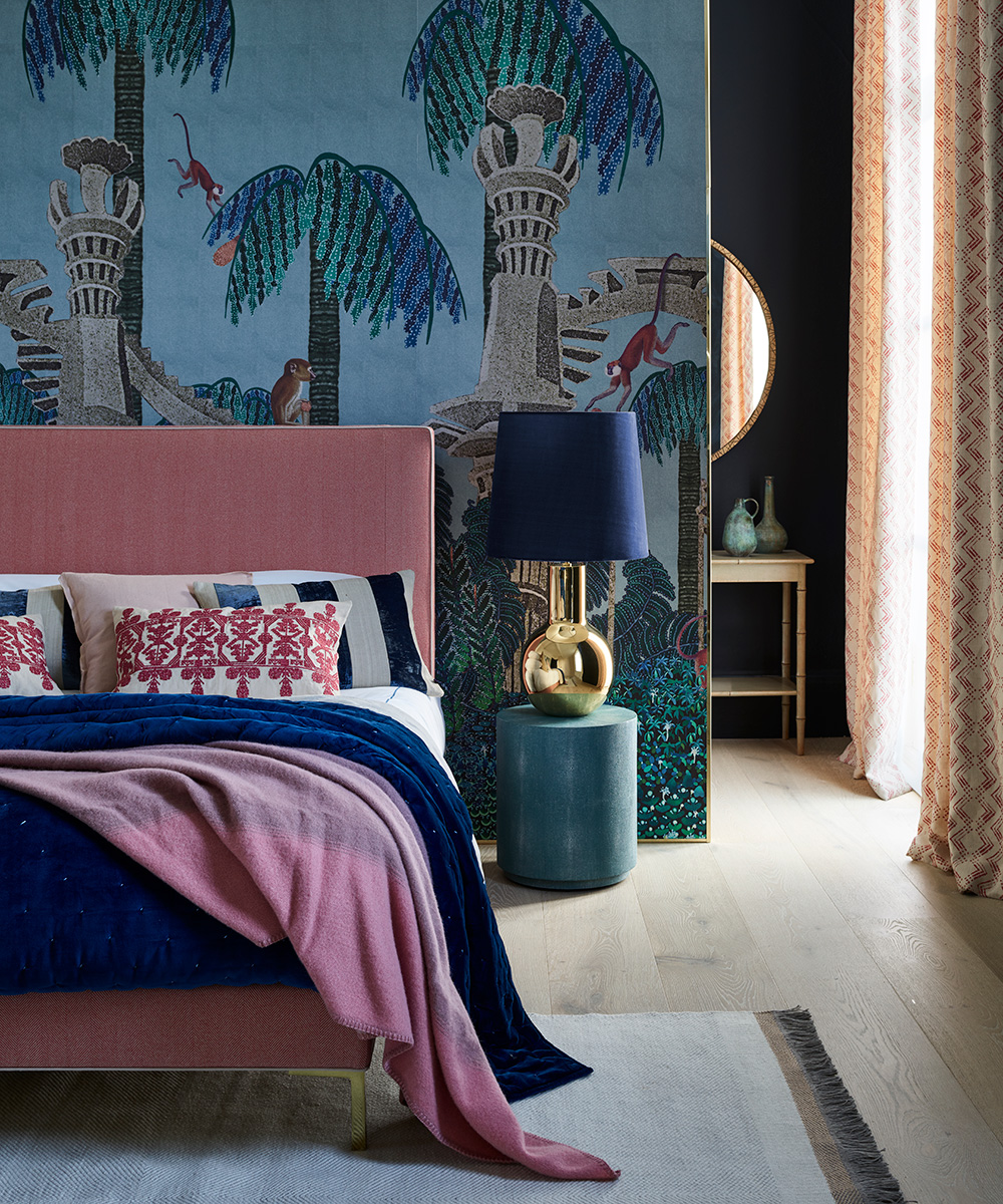 A bedroom with a colourful wall mural and a pink bed