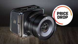Hasselblad 907X & CFV 100C on a wooden surface with the text balloon "Price Drop"