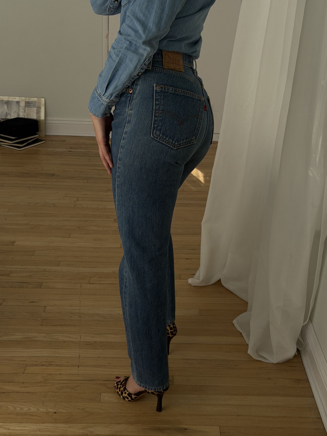 Kathryn Zahorak posing in mirror wearing denim shirt and jeans and leopard print heels