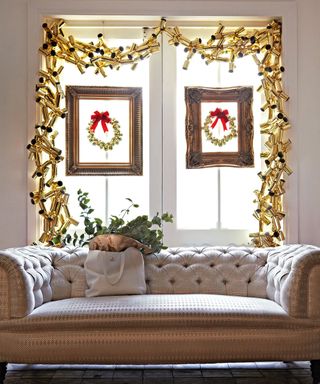 Christmas window decor ideas with a garland made from gold crackers and with framed wreaths on each window