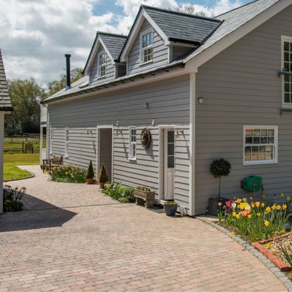 Block paving driveway front garden next to gravel area with spring bulbs including daffodils