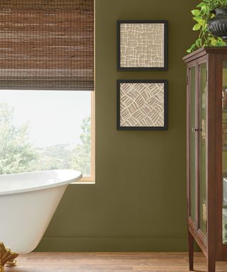 bathroom with olive green walls, free-standing white bath, wooden decor