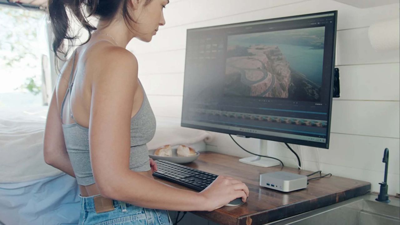 A woman working on a Geekom A8 mini PC in video editing software.