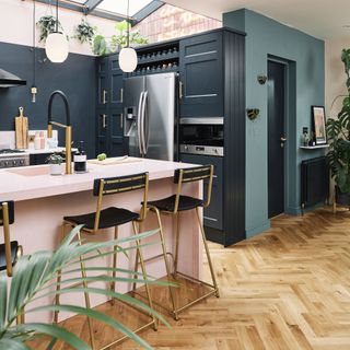 Navy kitchen with pink island and stools.