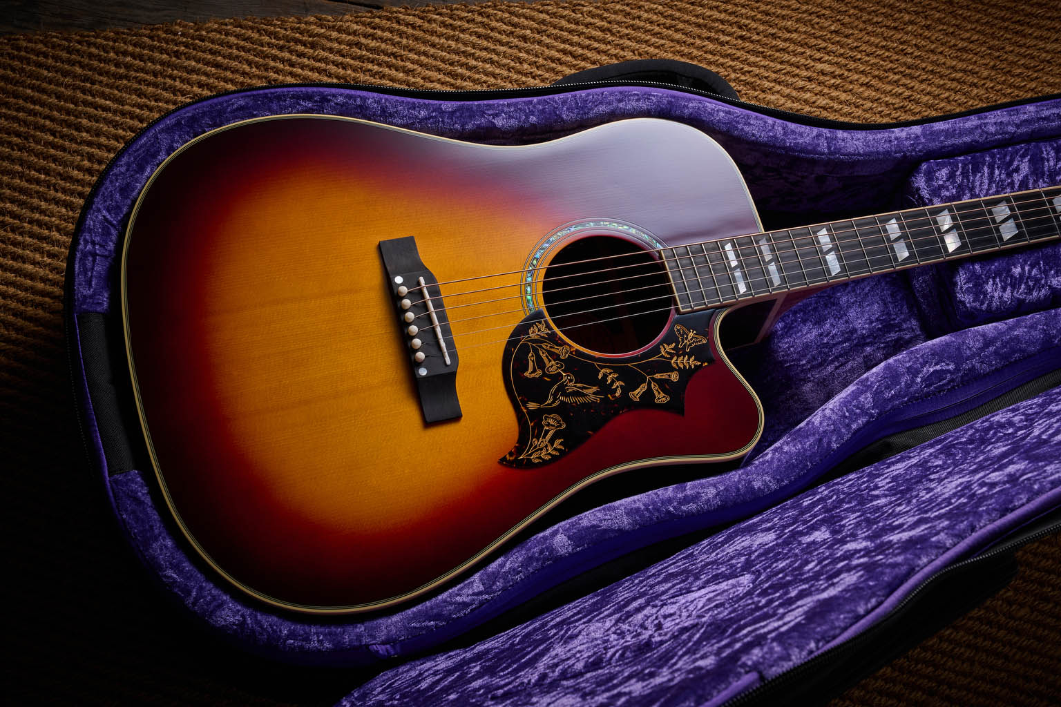 The Epiphone Inspired by Gibson Custom Hummingbird photographed in all its glory, in close-up and against a wheat-coloured rug.