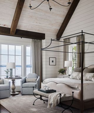 neutral bedroom with white wood walls, high ceilings and four poster bed