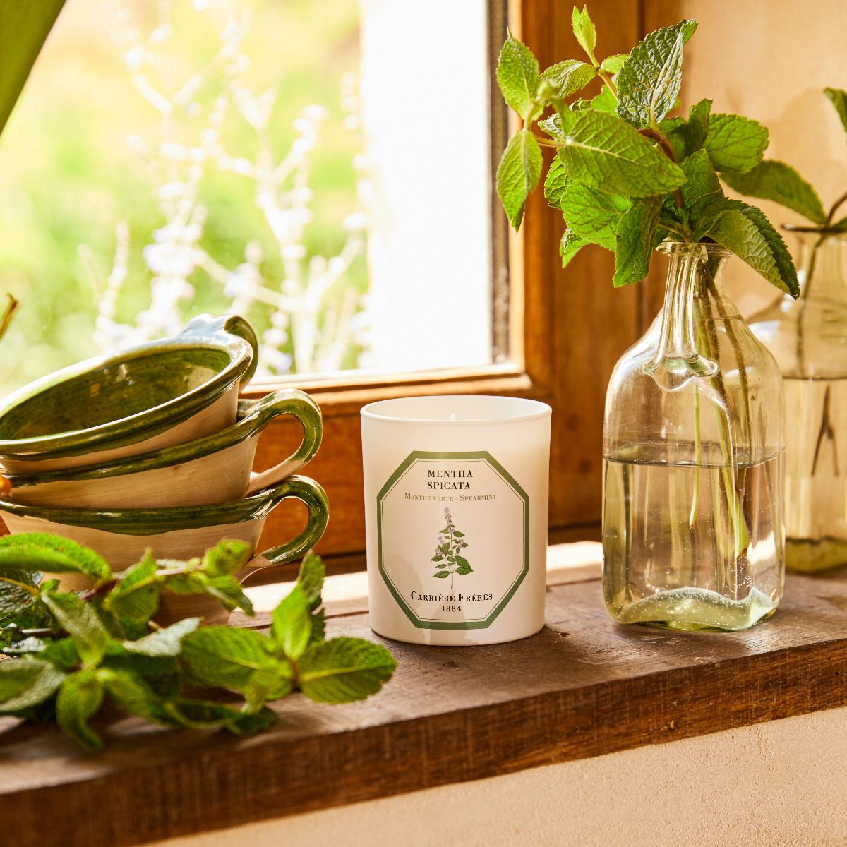 candle on window sill with mint leaves
