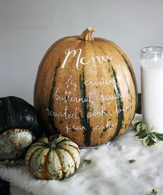 A pumpkin / squash /gourd with white paint text depicting dinner menu