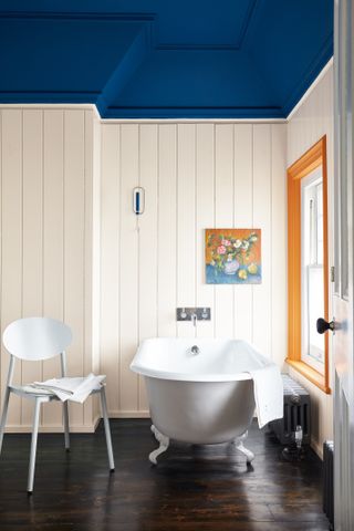 White bathroom with deep blue ceiling and orange window frame