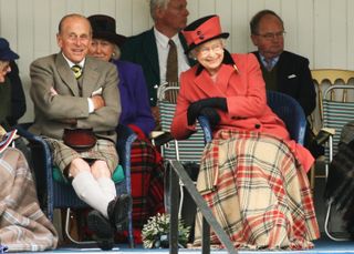 Queen Elizabeth II and Prince Philip, Duke of Edinburgh laugh as they watch the games during the Annual Braemar Highland Gathering