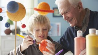 Kid and grandparent creating 3D model of solar system