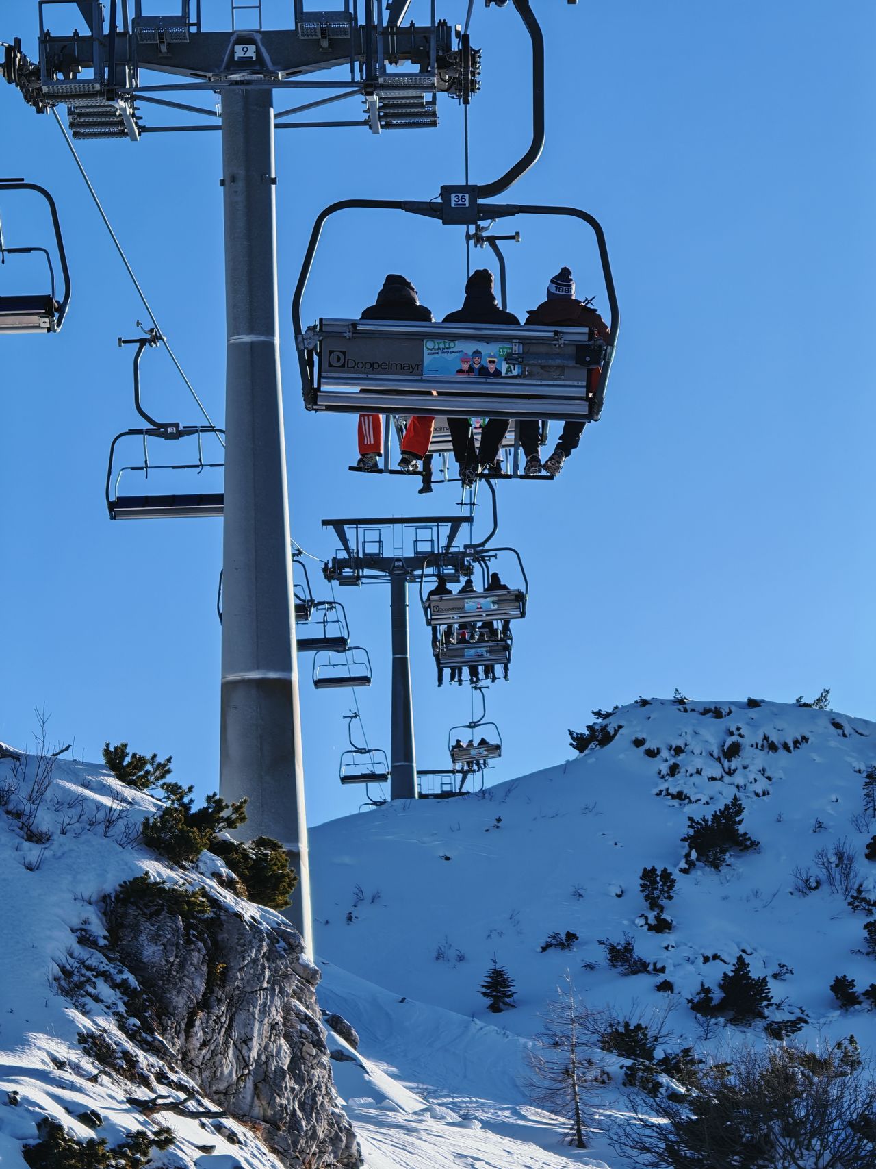 People riding a ski lift across snowy mountains