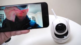NetVue Orb Mini Home Security Camera next to an iPhone with the app on screen