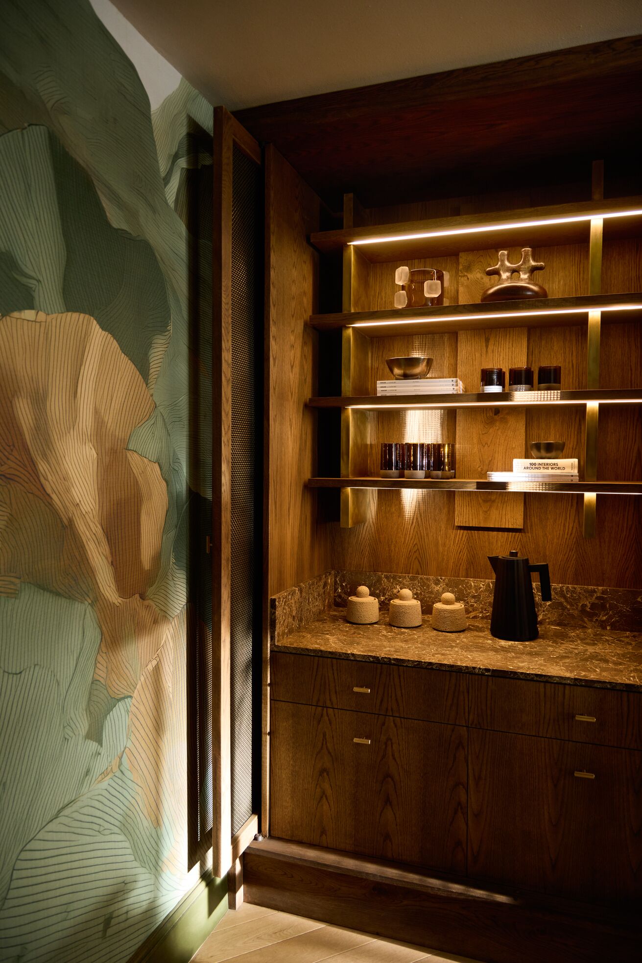 A series of shots capturing a young man dressed in patterned, or color-blocky, clothing, either standing in the sun-lit outdoor areas of a lush hotel, or inside a colorfully decorated suite filled with collectibles, artworks, and textural touches, or the interiors of that very space.