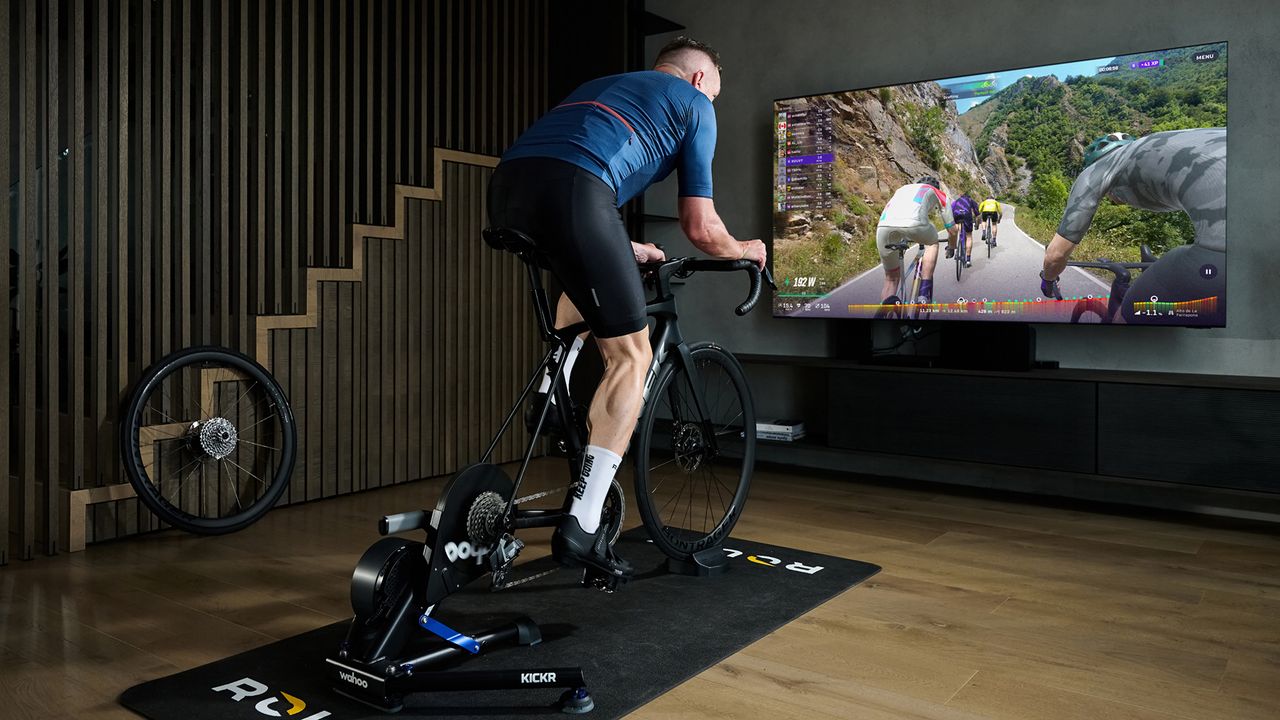 Man riding indoors, using Rouvy on large screen