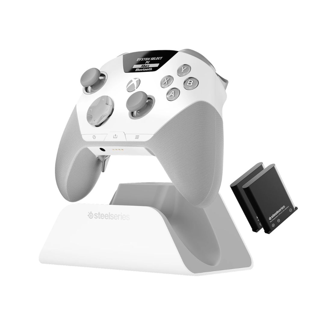 The white SteelSeries Aeon Pro controller on its charging stand and next to its battery packs