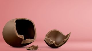 Milk chocolate Easter egg cracked open to reveal insides, pieces scattered around