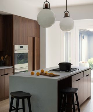 kitchen with walnut cabinetry and white island with black bar stools