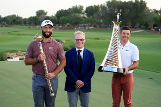 Jon Rahm, Keith Pelley and Rory McIlroy stand alongside trophies on the 18th green at Jumeriah Golf Estates after DP World Tour Championship.