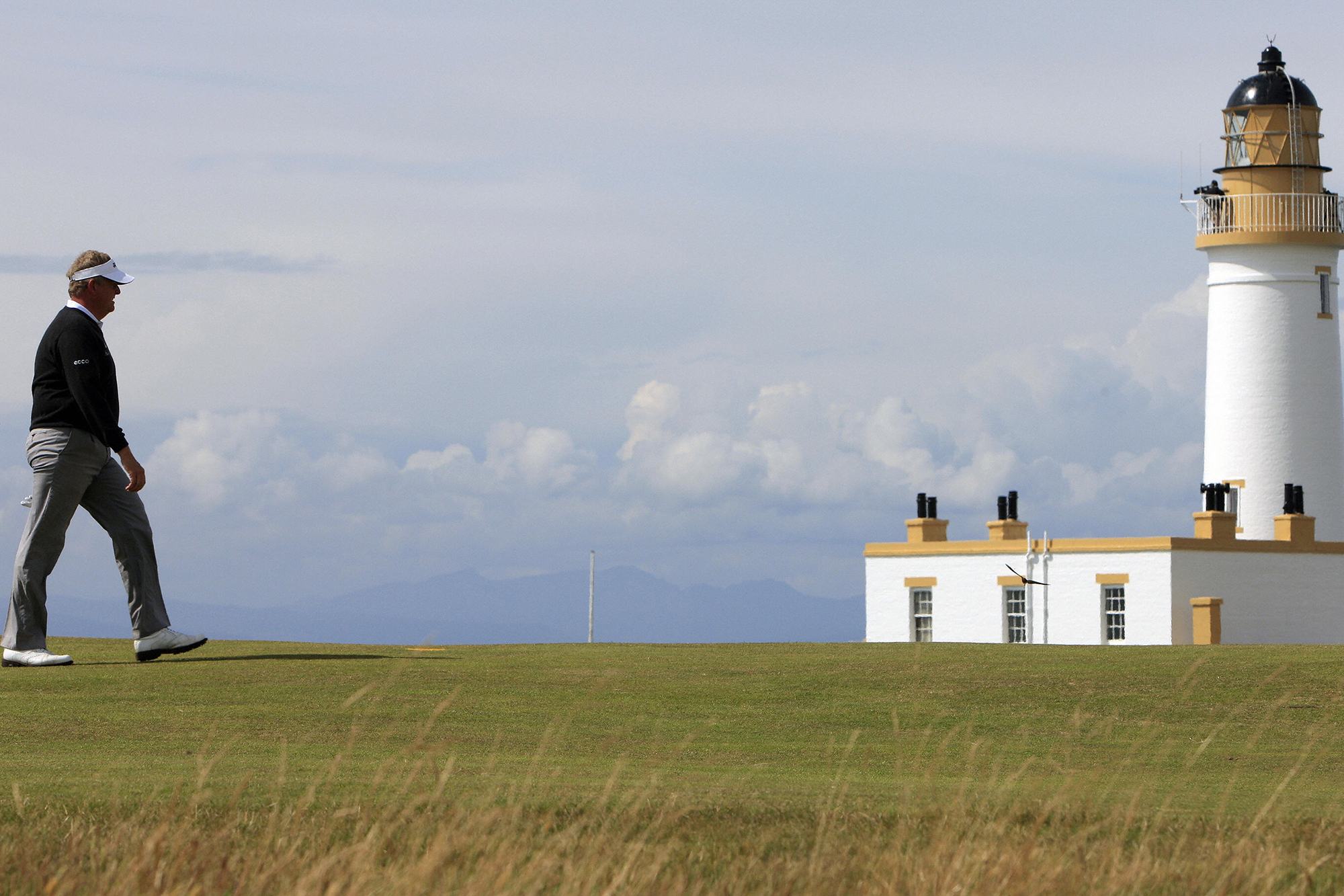 Colin Montgomerie walking along the fairway in front of the famous lighthouse at Trump Turnberry