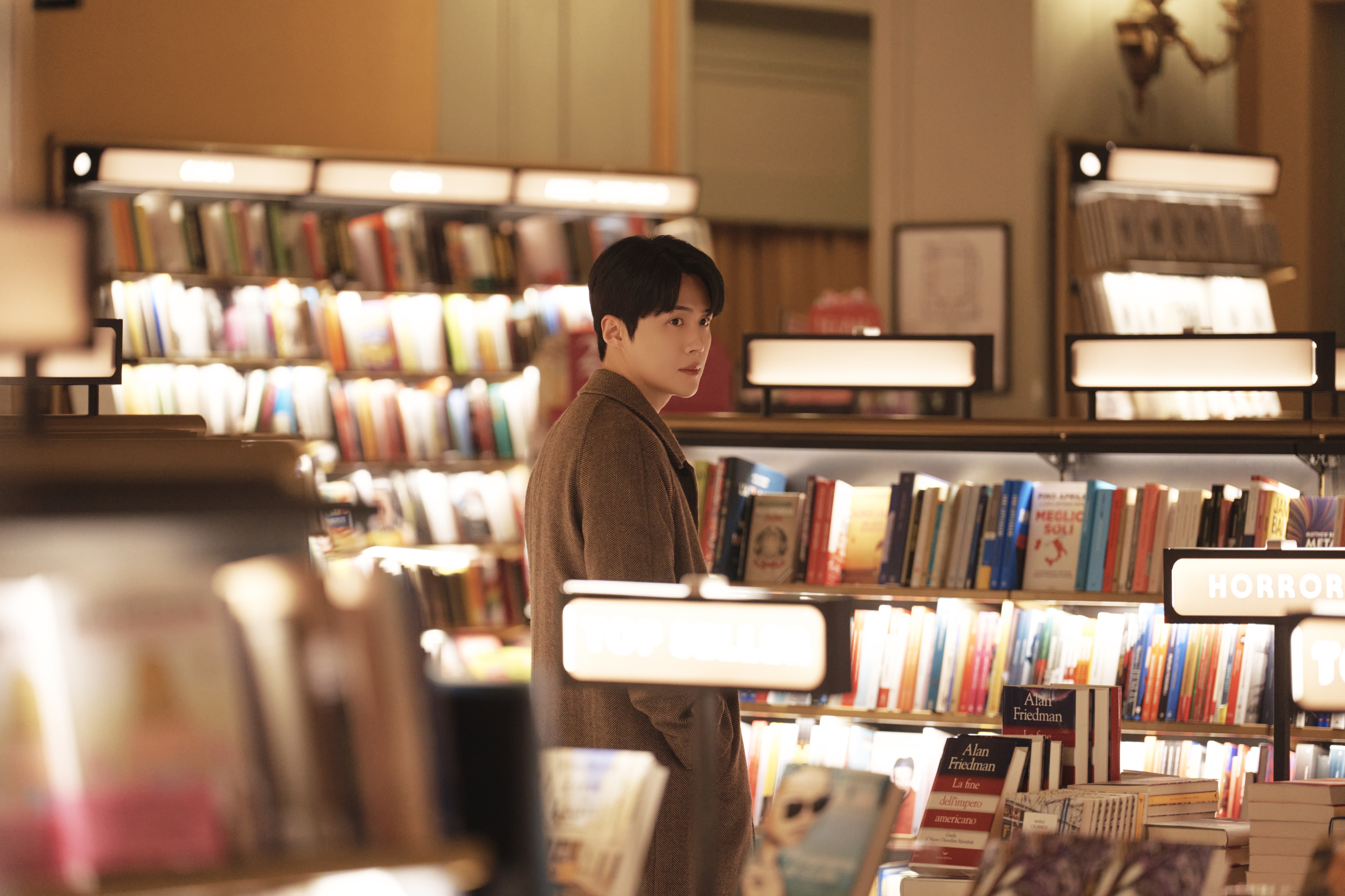 A man (Kim Seon-ho as Joo Ho-jin) stands amid the shelves in an French bookstore, in the Netflix K-drama 'Can This Love Be Translated?'