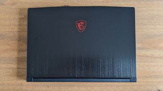 A black MSI GF63 Thin laptop on a wooden desk