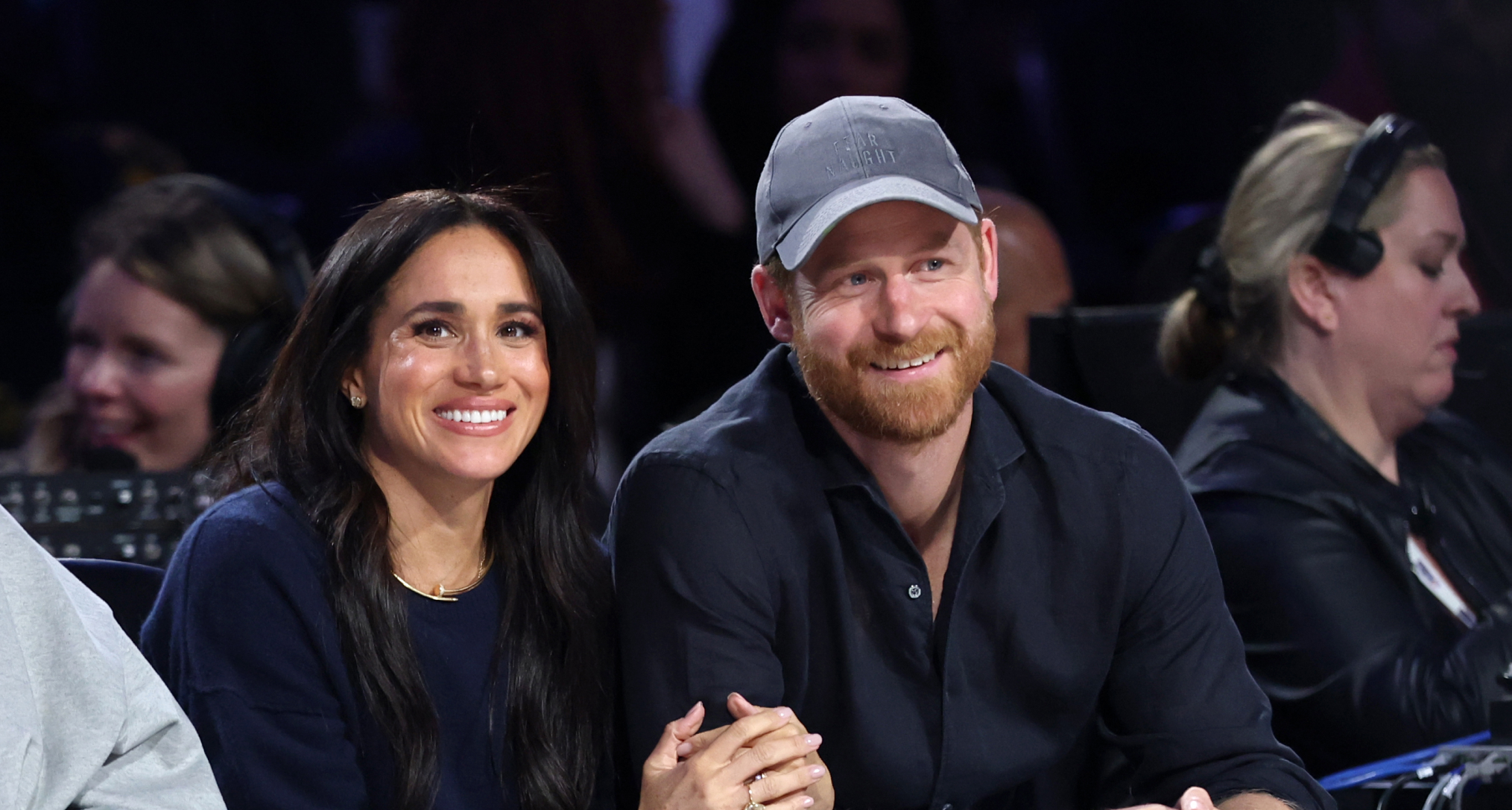 Prince Harry and Meghan Markle sitting next to each other in black outfits