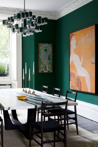 green dining room with orange wall art and green walls