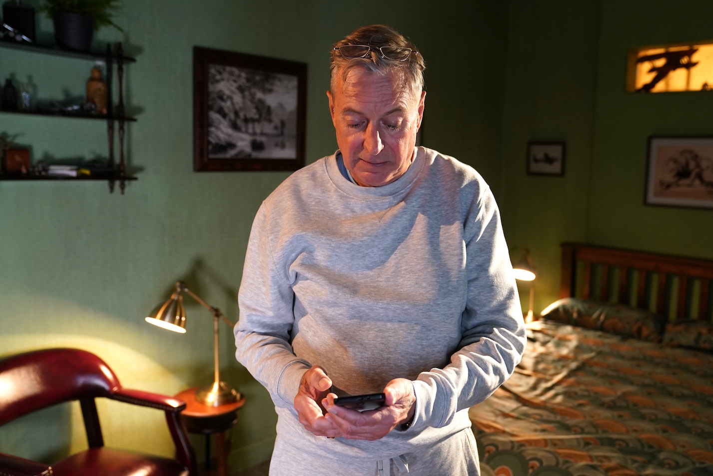 Froggy in his prison cell looking at a phone.