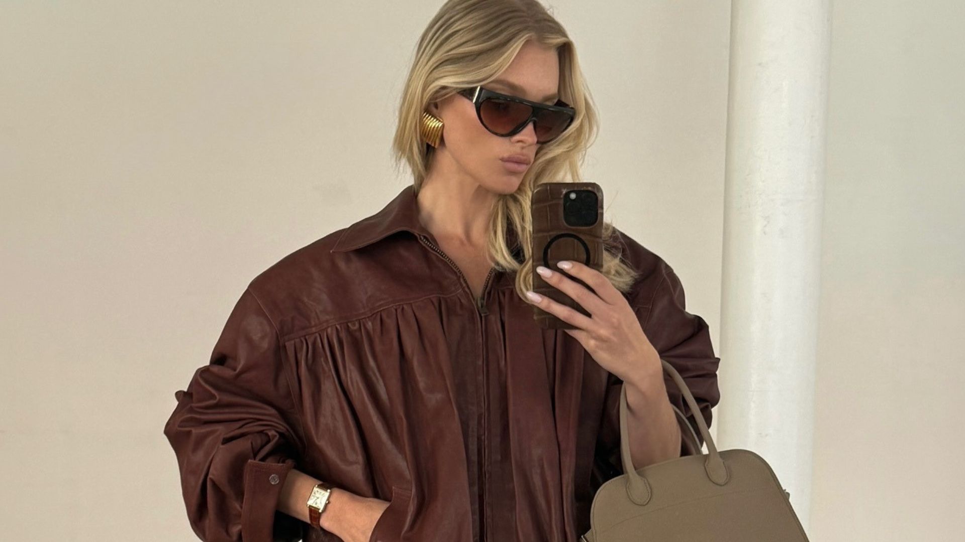 Elsa Hosk takes a mirror selfie wearing a brown leather jacket with a brown leather pencil skirt.