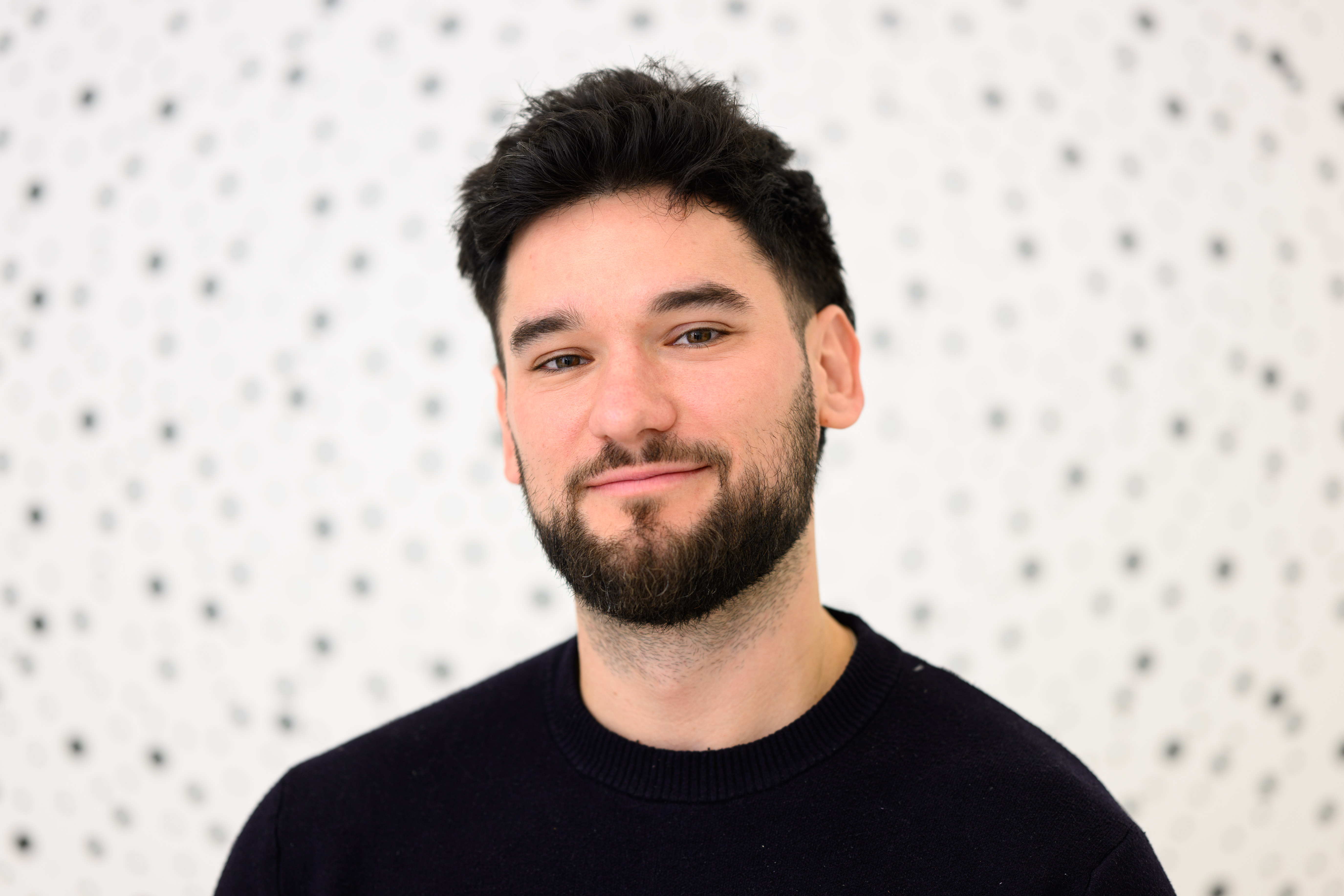 man with beard and a dark shirt on a spotty background