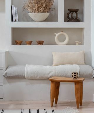 make your home feel like a sanctuary, white living space with alcoves, artisanal objects, seated area with cushions, wooden stool