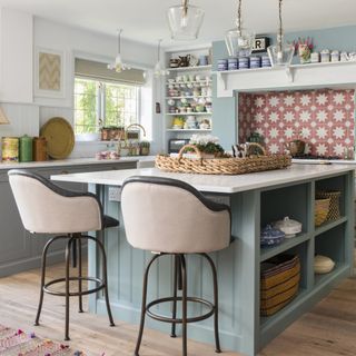Blue kitchen with kitchen island and pink stools