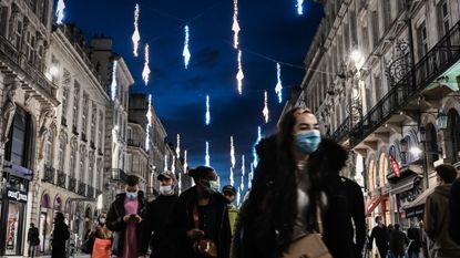 Shoppers walk under Christmas decorations in Bordeaux