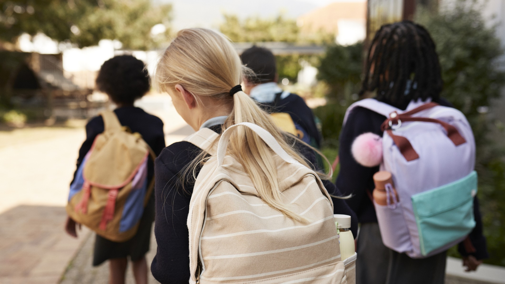 Rear view of girls wearing backbacks and going to school