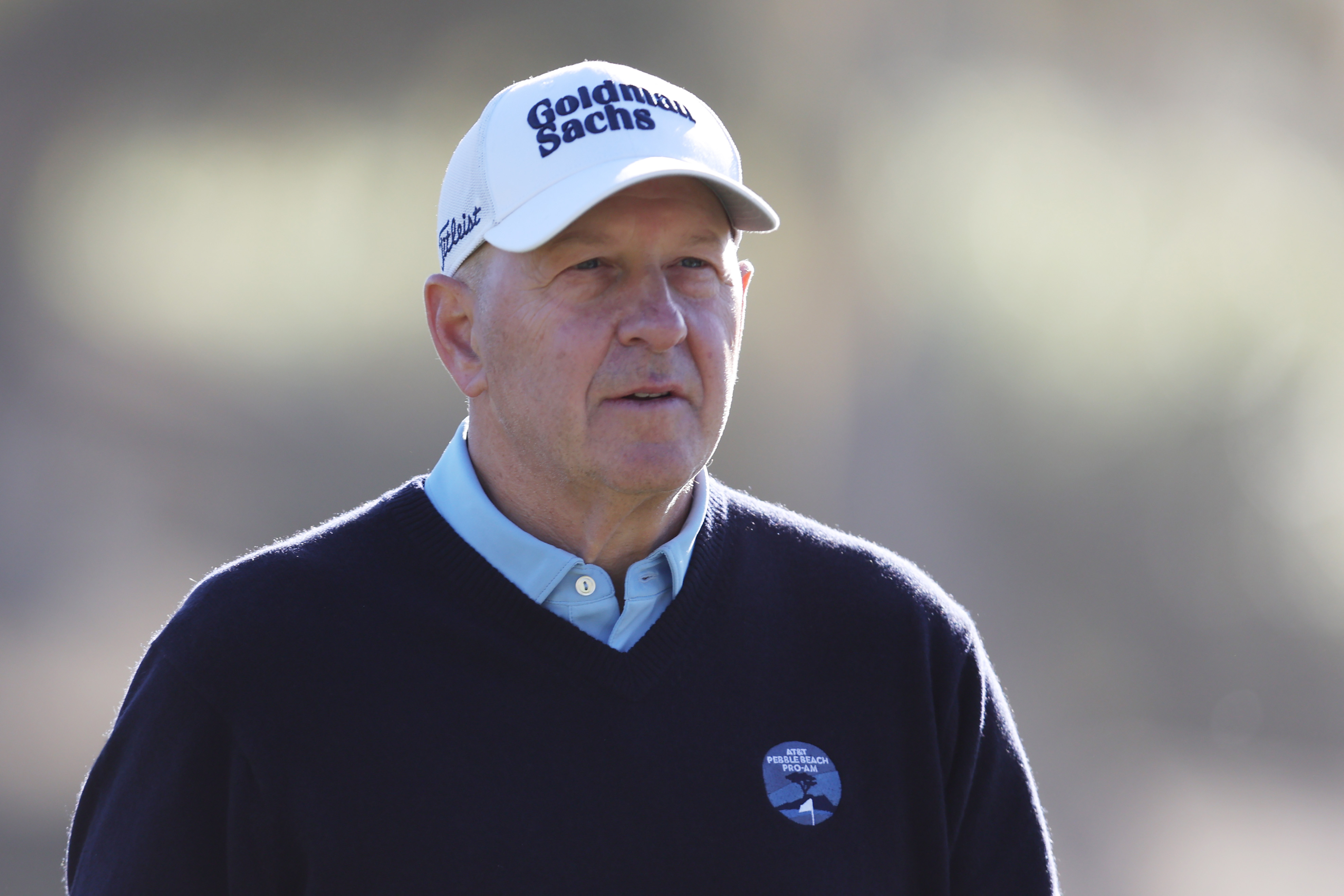 David Solomon wearing a white cap and navy sweater on the golf course