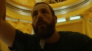 a bearded man looks confused inside a cramped spacecraft bathed in gold light