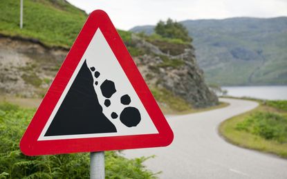 There may be trouble ahead - a rural road sign warning of a danger of falling rocks around the corner on a road in Scotland.