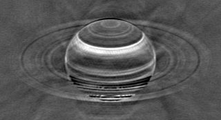 a black and white image of a ringed planet whose surface is marked by different colored bands
