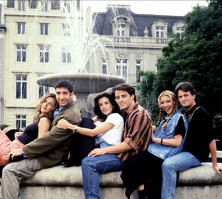 the cast of friends posing together by a fountain in the 90s