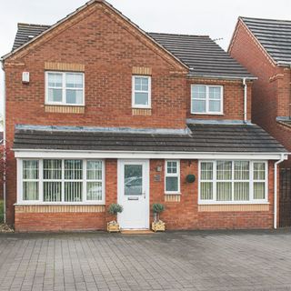 Exterior of a brick built modern house, with a paved driveway