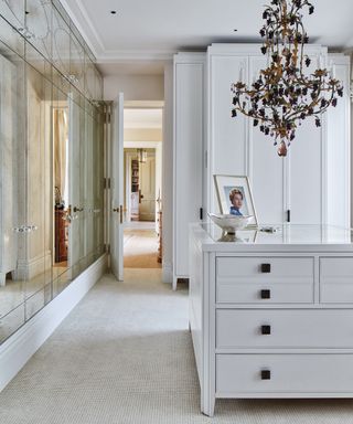 A white bedroom idea with white and mirrored wardrobe and black chandelier