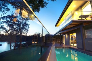 pool fence ideas: glass fence surrounding waterfront pool